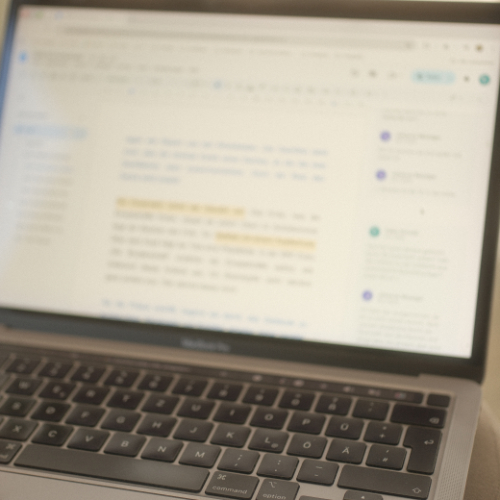 Blurred laptop screen displaying a text editor with a visible keyboard.